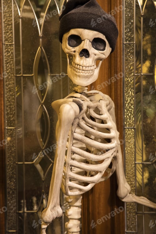 Preview: Halloween Skeleton Greeting At The Door Wearing A Knitted Hat