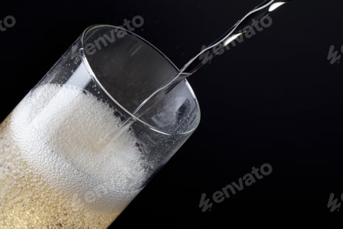 Preview: Champagne Being Poured In A Glass Against Black Background.