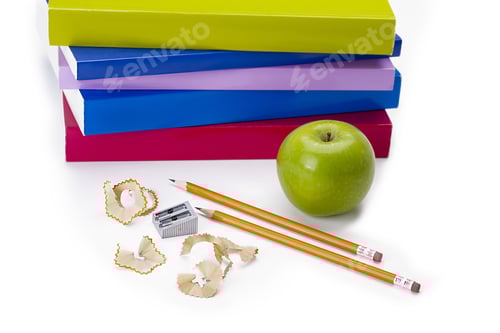 Visualização: Dois lápis afiados e uma maçã verde na frente de uma pilha de livros indicando estudo ou aprendizado.