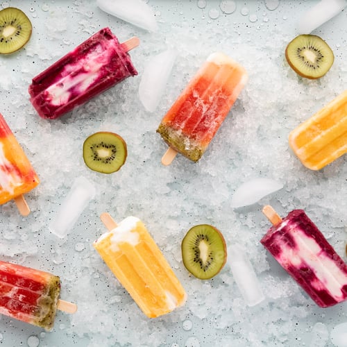 Preview: Top Down View Of Various Homemade Popsicles On A Tray Of Ice With Slices Of Kiwi.