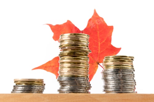 Preview: Rough Stacks Of Unidentified Gold And Silver Coins On A Wooden Table With A Red Maple Leaf Isolated