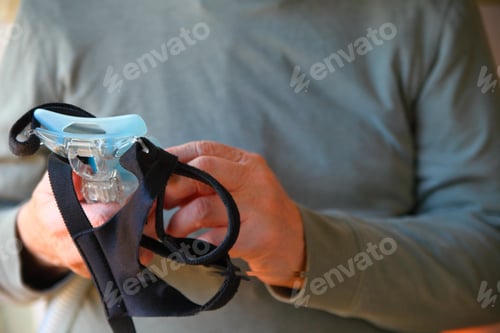 Preview: A Man Holds His Sleep Apnea Face Mask And Headgear
