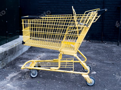 Preview: A Yellow Shopping Cart By A Black Brick Wall