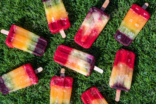 Preview: A Top Down View Of An Assortment Of Rainbow Popsicles Against Green Grass.