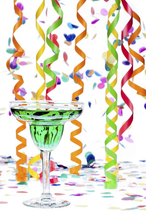 Preview: Close-Up Shot Of Martini With Green Alcohol While Colorful Decorative Streamers And Confetti In