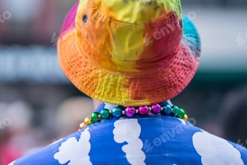 Preview: Man In The Crowd Celebrating Pride Parade. Wearing Colorful Rainbow Hat, Necklace And A Blue Shirt