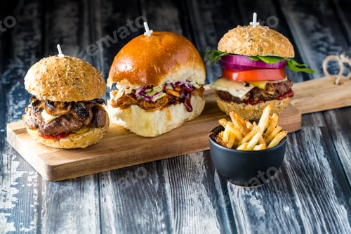 Preview: Close Up View Of Three Hamburger Sliders With Various Fillings On Top Of A Wooden Cutting Board