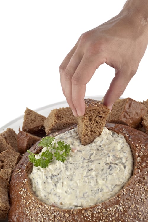 Preview: Close-Up Image Of A Human Hand With A Bread Cube On Pumpernickel Spinach Dip