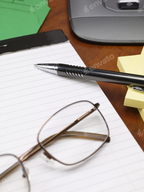 Preview: Close-Up Cropped Image Of Notepad And Pen With Spectacles On Wooden Desk.