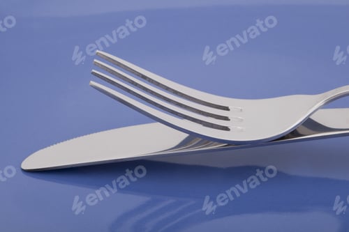 Preview: Close-Up Shot To The Silver Fork And Knife On A Blue Glass Table