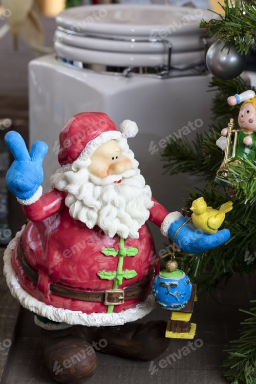 Preview: Brightly Colored Santa Claus Ornament Holding Presents Next To A Christmas Tree
