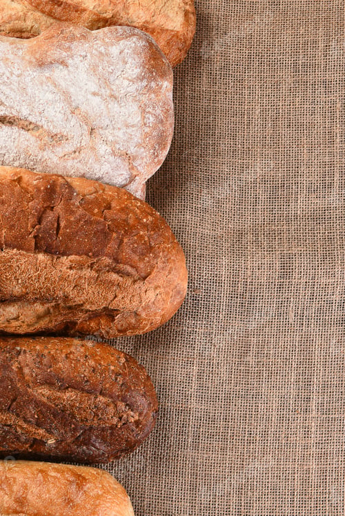 Preview: Five Different Loaves Of Bread On A Wood Table With Copy Space. Vertical Format.