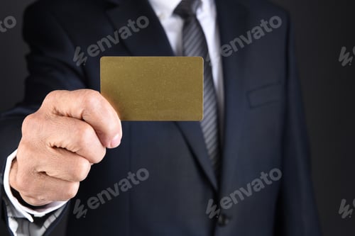 Preview: Closeup Of A Businessman Holding A Blank Gold Card In Front Of His Toso. Man Is Unrecognizable.