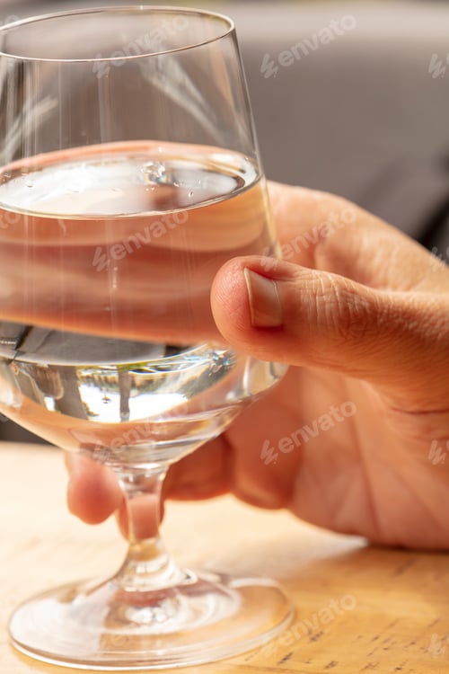 Preview: Hand Of A Person Holding A Wine Glass Of Water In A Restaurant