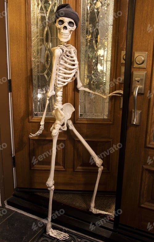 Preview: Halloween Skeleton Greeting At The Door Wearing A Knitted Hat