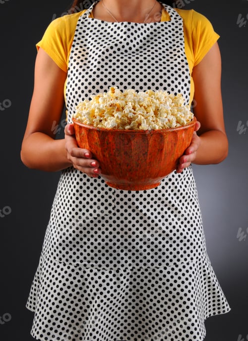 Preview: Closeup Of A Homemaker In An Apron Holding A Bowl Of Popcorn. Vertical Format Over A Light To Dark