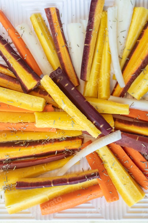 Preview: Colorful Yellow, Orange, Red And White Sliced Raw Carrots Plated And Sprinkled With Dry Rosemary Heb