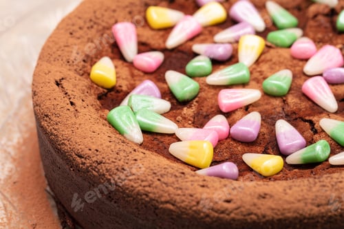 Preview: Flourless Dark Chocolate Cake With Pastel Colored Candy Corn On Top On A Clear Serving Plate