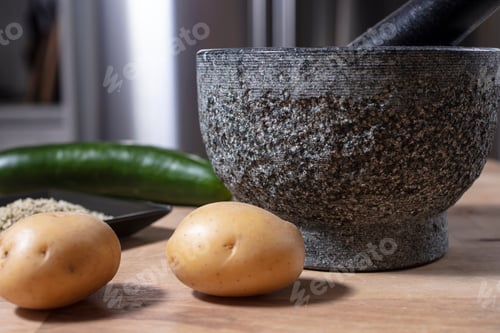 Preview: Mortar And Pestle Made Of Stone On A Kitchen Counter With Potatoe, Hemp Seeds And Cucumber