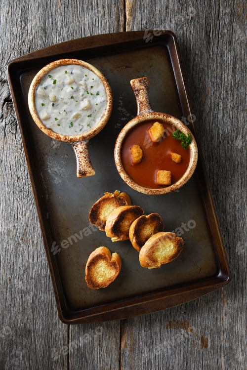 Preview: Two Fresh Homemade Bowls Of Clam Chowder And Tomato Soup With Garlic Toast On A Metal Baking Sheet.