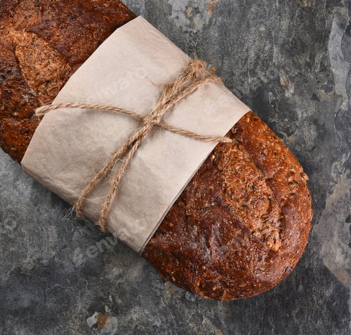 Preview: Flat Lay Still Life Of A Loaf Of Multi-Grain Bread On Slate Background.