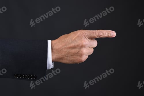 Preview: Closeup Of A Mans Hand Pointing. Dark Suit Over A Dark Gray Background.