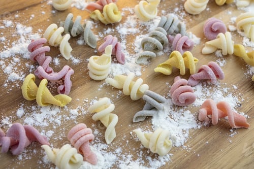 Preview: Curly And Twisted Pasta Shapes On A Cutting Board In Various Colors Of Pink, Yellow, Green And White