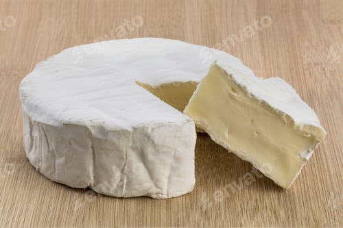 Preview: Closeup Of A Round Of Brie Cheese With A Wedge Cut Out On A Wooden Table