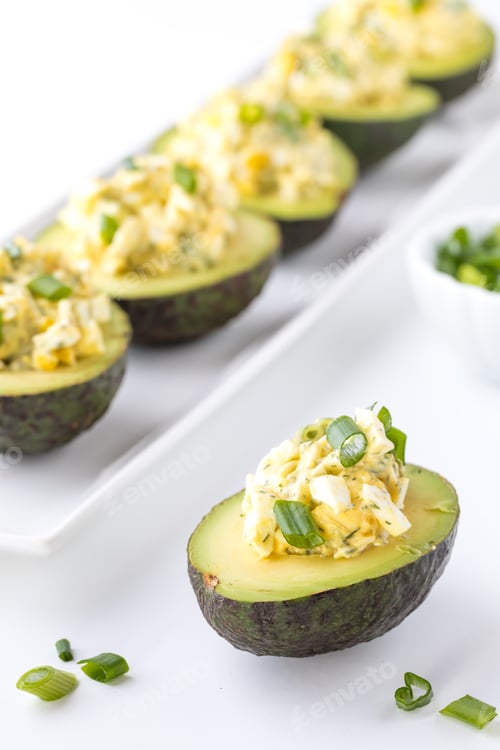 Preview: Close Up Of Egg Salad In Half An Avocado Garnished With Green Onion Ready For Eating.