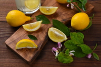 Aperçu: Nature morte d'un groupe de citrons, entiers et coupés, sur une planche à découper. Feuilles et fleurs de citron avec un