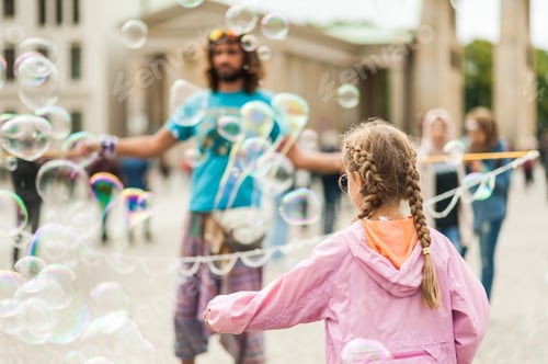 Preview: Children Playing With Colorful Soap Bubbles Floating In The Foreground. Street Performer, Busker