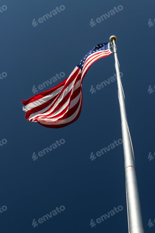 Preview: American Flag On A Flagpole Blowing In The Wind Against A Blue Sky