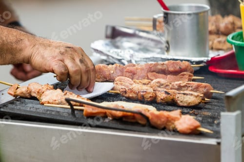Preview: Close Up Of A Local Mans Hands Grilling Meat Outdoors