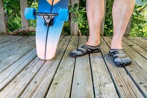 Preview: Legs Of Mature Male With A Cruising Longboard On A Wooden Patio, Recreation Concept