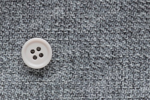 Preview: Clothes Sewing Button On A Gray Fabric Swatch Background
