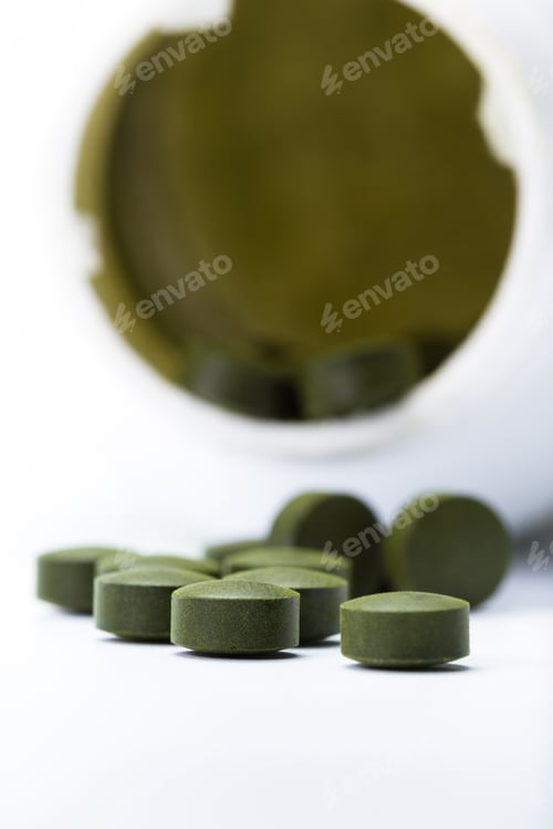 Preview: Close Up Of A Group Of Fermented Chlorella Tablets Isolated On A White Background
