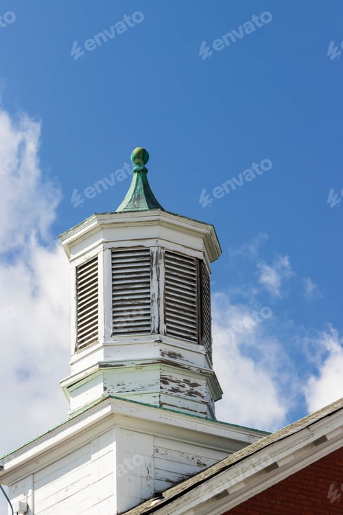 Preview: Vented Wooden Cupola On Top Of An Old Brick Building Against A Blue Sky