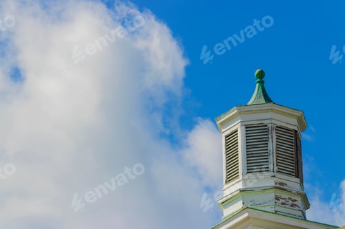 Preview: Vented Wooden Cupola On Top Of An Old Brick Building Against A Blue Sky