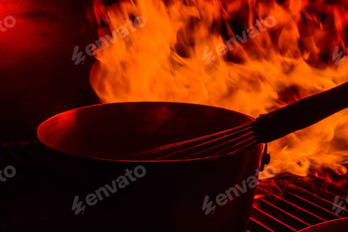 Preview: Fire On The Grill - A Sauce Pan With A Whisk On The Grill As Fire Flares Around It