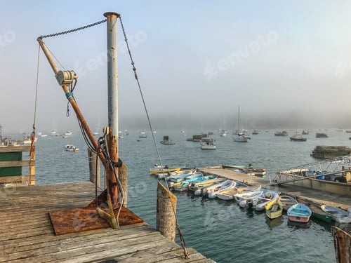 Preview: Fog Rolling Into The Harbor Filled With Boats With A Dock With A Loading Pulley In The Foreground