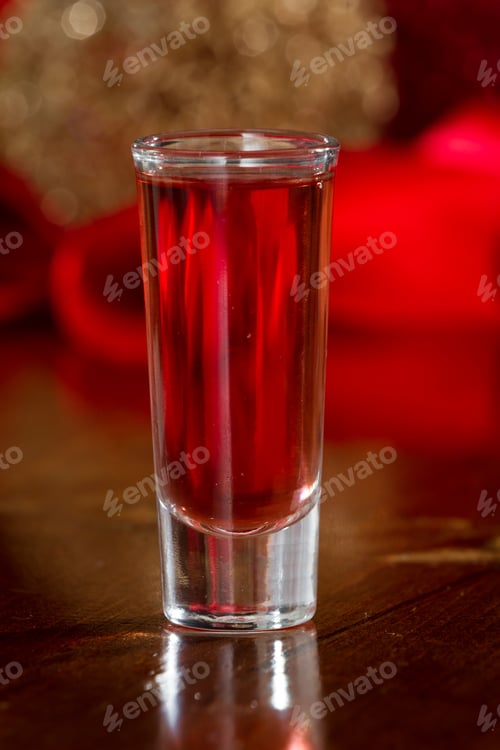 Preview: Red Holiday Shot Served In A Clear Tall Glass With An Out Of Focus Christmas Background