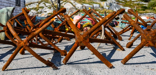 Preview: An Abstract Of Rusting Anchors On A Seaside Dock With Multicolored Ropes And Buoys In The Background