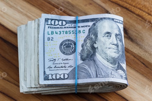 Preview: Close Up Of A Roll Of Cash Golden In Half On A Wooden Table