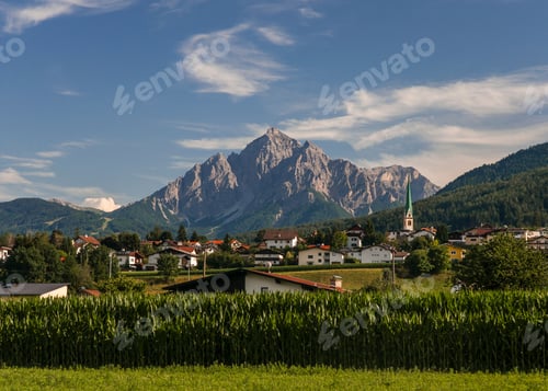 Preview: Beautiful Small, Old Traditional Town With Fields In The Foreground And A Steep Rocky Mountain In