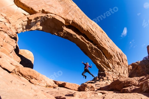 Preview: Woman In A Celebratory Jump At The Base Of North Window In Arches National Park