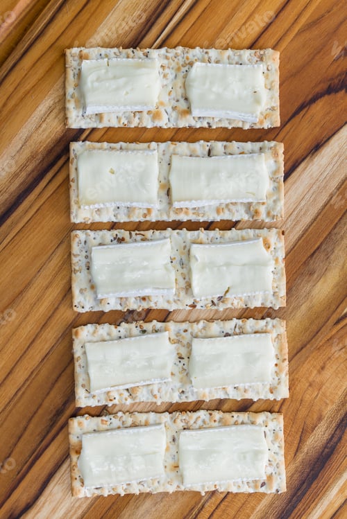 Preview: Close Up Of Slices Of Brie Cheese On Everything Crackers On A Wooden Background