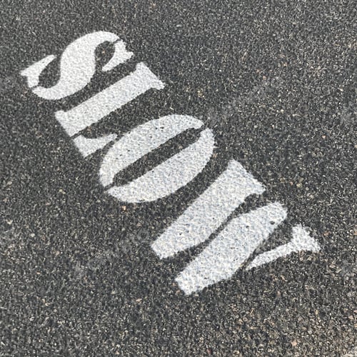 Preview: Stenciled Sign Saying “Slow” Stenciled On Asphalt