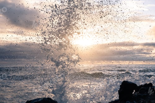 Preview: Waves Splashing Against The Rocks On The Shore In The Early Morning With The Sun Peaking Through