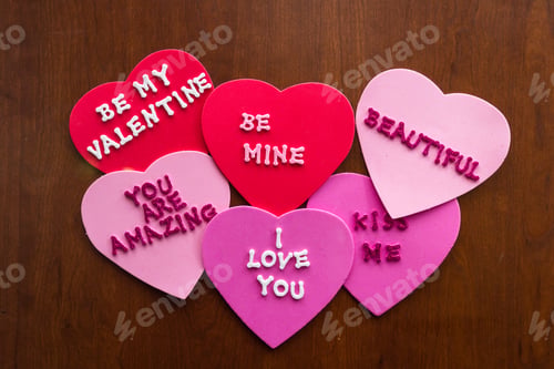 Preview: Romantic Messages Written With Glitter Letters On Colorful Hearts Stuck On A Wooden Background