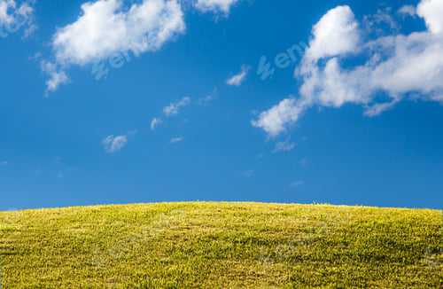 Preview: Bright Green Sunlit Grass Hill With Blue Sky And Clouds With Copy Space